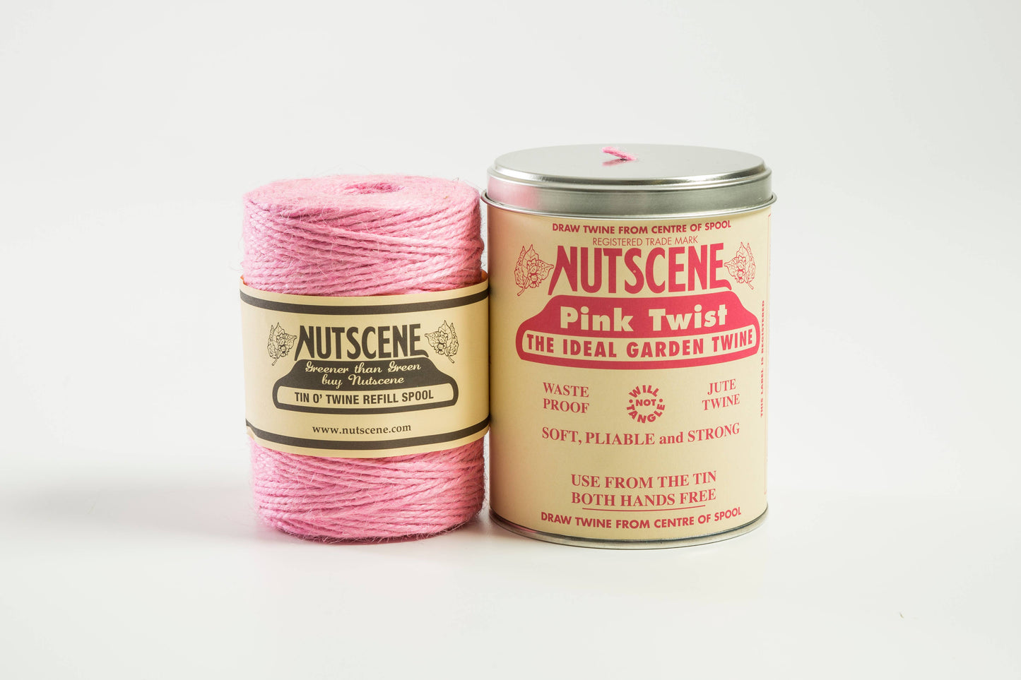Eine Spule rosafarbener Gartenschnur von Nutscene Twines Ltd. wird neben einer ikonischen Dose mit Nutscene Twine – Schnur in einer Dose (490 Fuß) – ausgestellt, beide mit Verpackung im Vintage-Stil und dem Branding von Nutscene Twines Ltd.