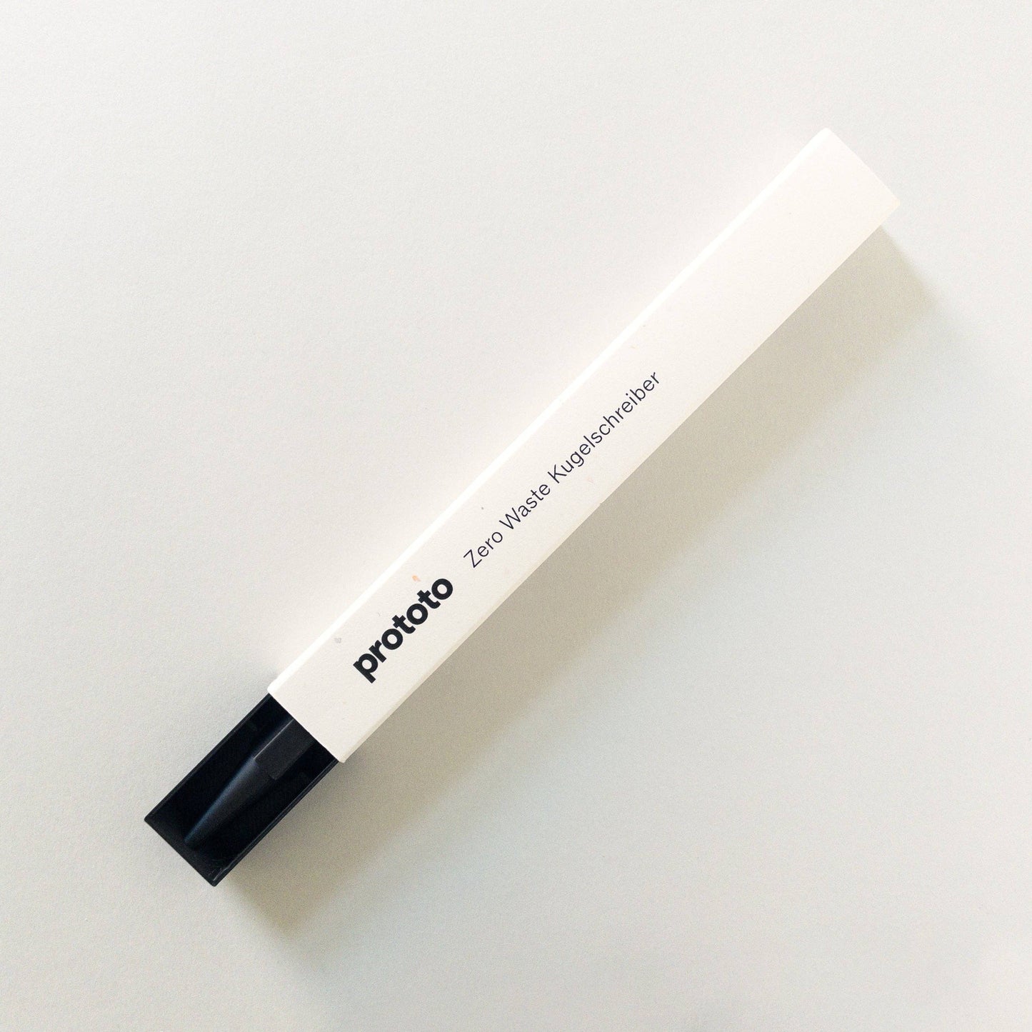 Der Prototo - Zero Waste Kugelschreiber in Schwarz, ein rechteckiger weißer Stift mit schwarzer Kappe von Prototo, besteht aus erdölfreiem Bioplastik und bietet ein klimaneutrales Schreiberlebnis. Abgebildet auf einem schlichten hellen Hintergrund.