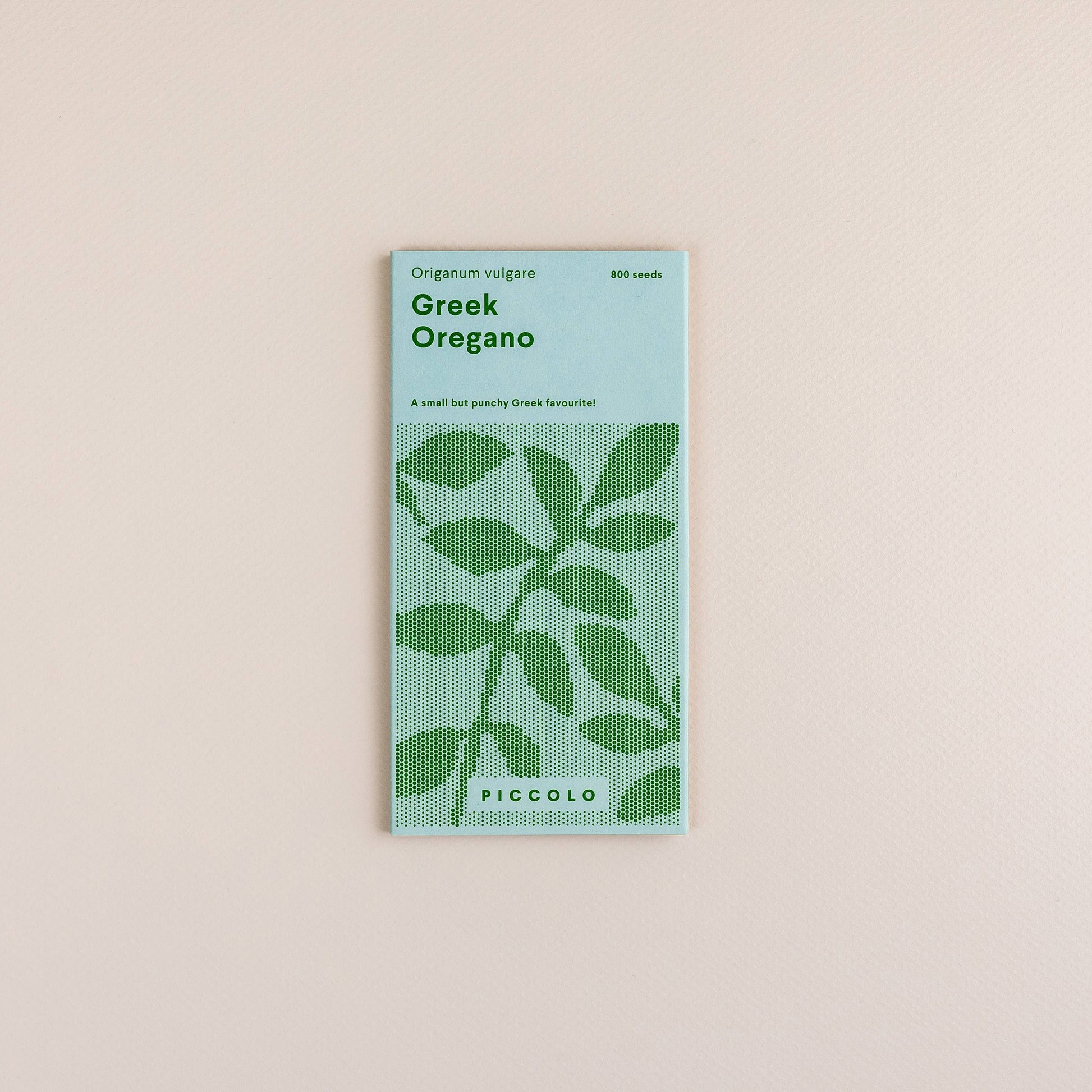 Eine Packung Piccolo Seeds - Oregano-Griechisch zeichnet sich durch ein minimalistisches Design mit grünem Text und einem stilisierten Blatt auf hellem Hintergrund aus. Der Markenname Piccolo Seeds steht am unteren Rand, perfekt für mediterrane Kräutergärten.