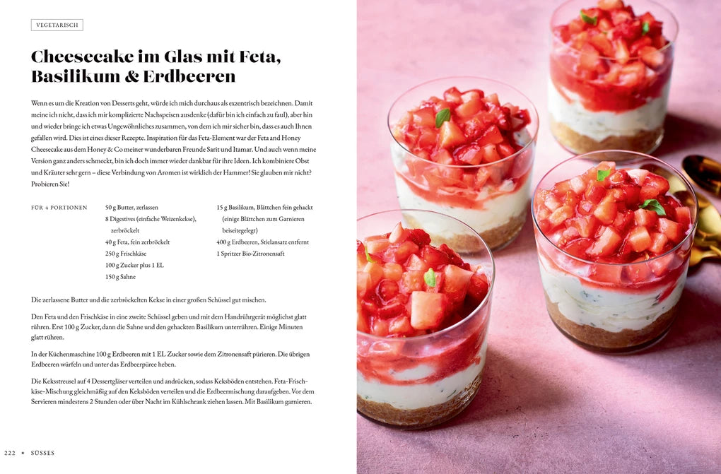 Fünf Gewürzküchen-Gläser des Hölker Verlags, jeweils geschichtet mit Bröselboden, cremigem Käsekuchen und gewürfelten roten Beeren. Inspiriert von den Rezepten von Sabrina Ghayour. Zusätzliche Gläser und frische Basilikumblätter auf einer rosa Fläche.