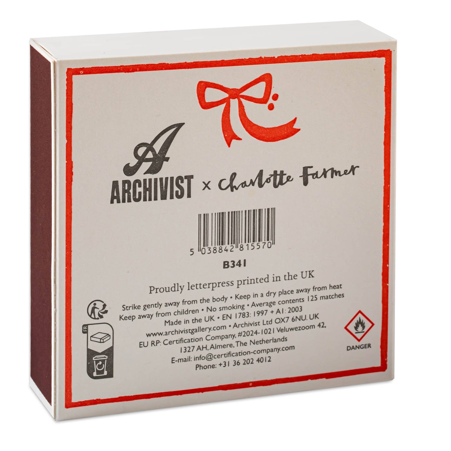 Auf der Rückseite des Archivist Gallery | Europe - Pudel Quadrat Weihnachts-Sicherheitsstreichhölzer🎄 befinden sich ein Branding, Sicherheitsinformationen, eine rote Schleife und ein Gefahrensymbol - ein ideales besonderes Streichhölzer oder ein festliches Geschenk für jeden Pudel-Fan.