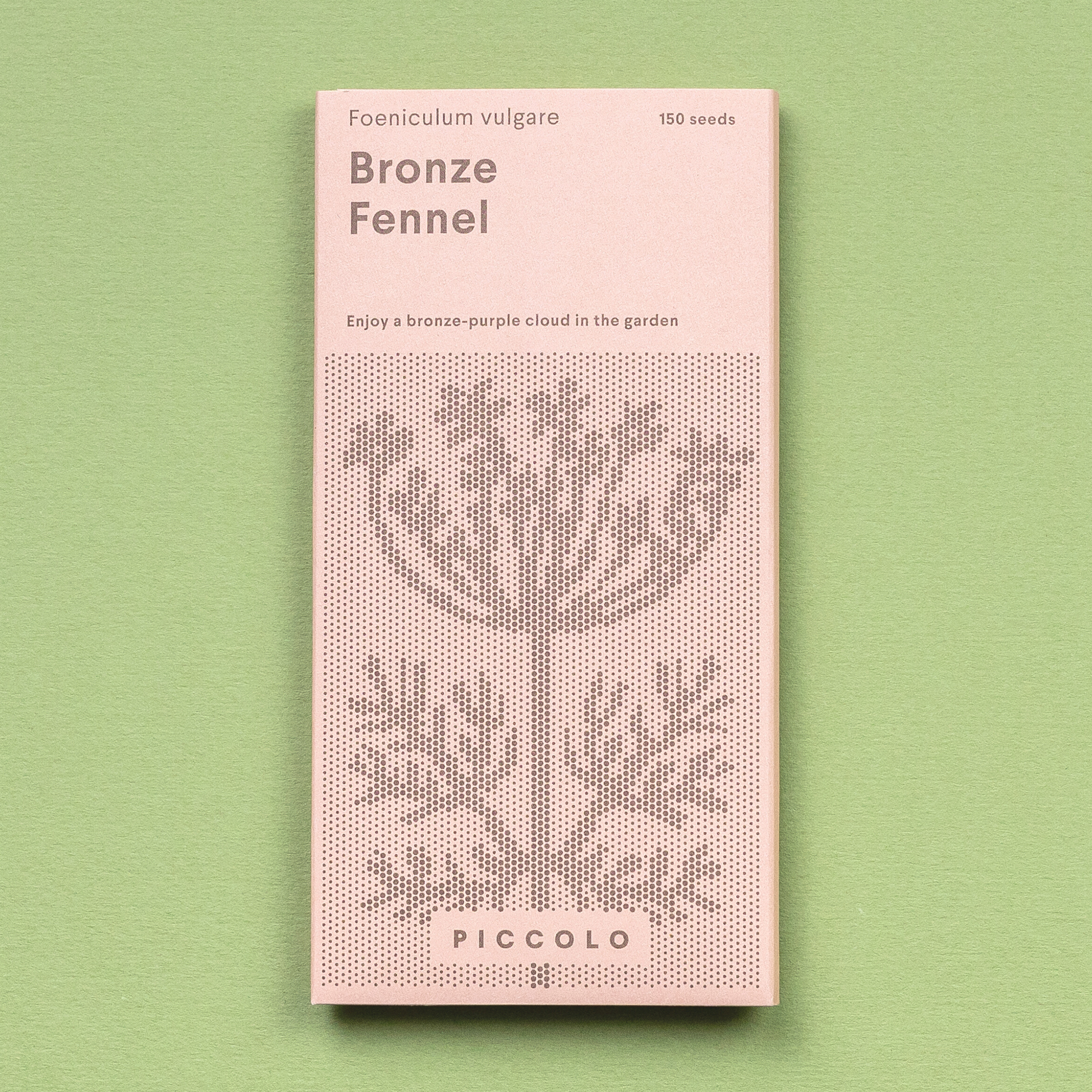 Eine rosa Piccolo Seeds - Fenchelbronze Packung mit einer gepunkteten Pflanzenillustration liegt auf einem hellgrünen Hintergrund. Die Vorderseite zeigt "Foeniculum vulgare, Bronzefenchel, 150 Samen" und hebt seinen charakteristischen Lakritzgeschmack hervor.