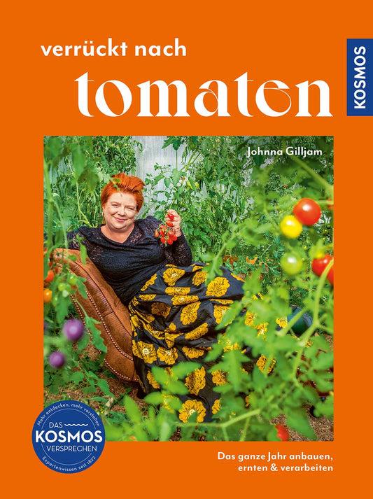 Eine lächelnde rothaarige Frau sitzt zwischen üppigen Tomatenpflanzen und hält eine Tomate. Sie trägt ein schwarzes Oberteil und einen gelb gemusterten Rock. Das orangefarbene Cover von "Verrückt nach Tomaten" aus dem Kosmos Verlag verspricht leckere Rezepte.