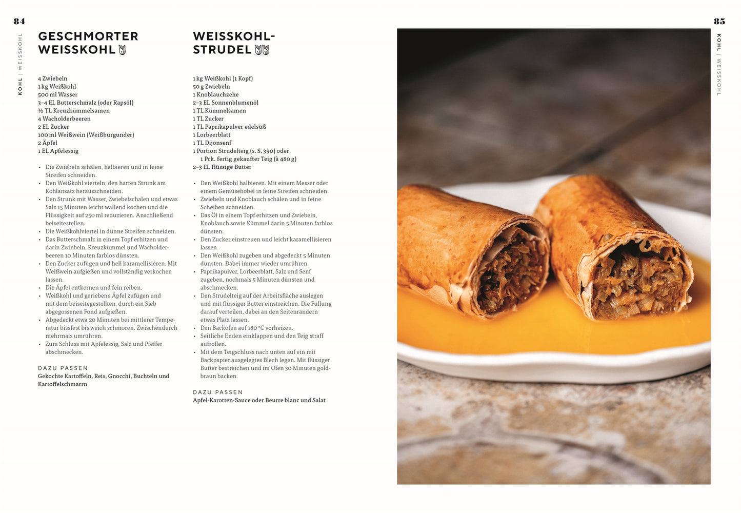 Eine Nahaufnahme von zwei Stücken Krautstrudel mit goldbrauner Kruste, inspiriert von Vegetarisch aus dem DK Verlag, aufgeschnitten, um eine herzhafte Füllung zu zeigen, und mit Orangensauce auf einem weißen Teller vor einem steinernen Hintergrund serviert.
