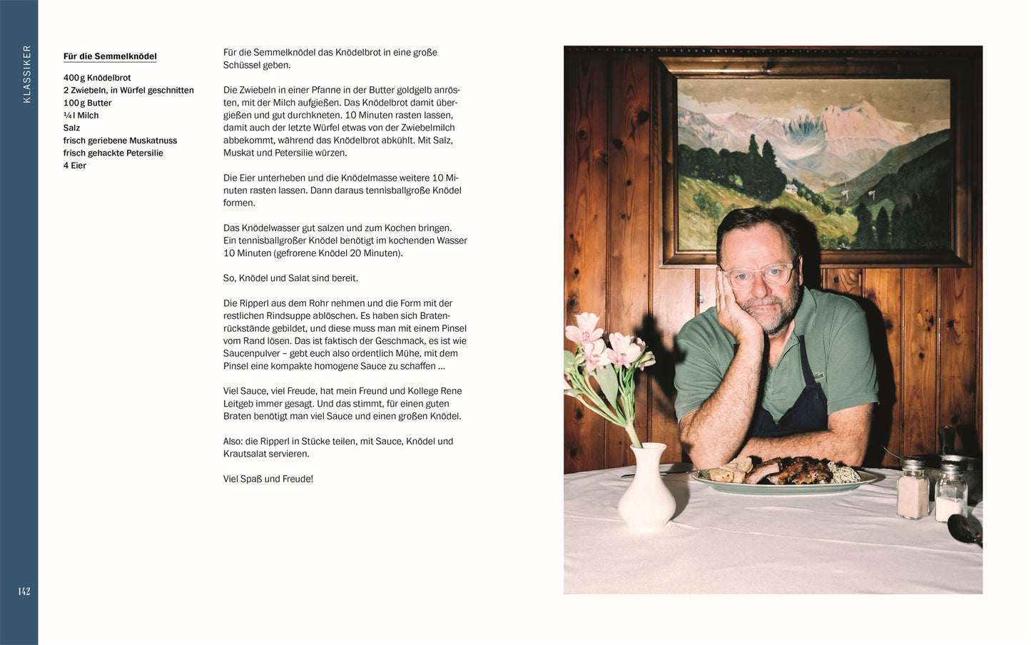Profikoch Sepp Schellhorn, Autor von „Sepp, was machst du?“ (DK Verlag), sitzt lächelnd an einem schön gedeckten Tisch – das perfekte Setting für Social Media Kochvideos vor rustikalem Holz und Landschaftsgemälde.