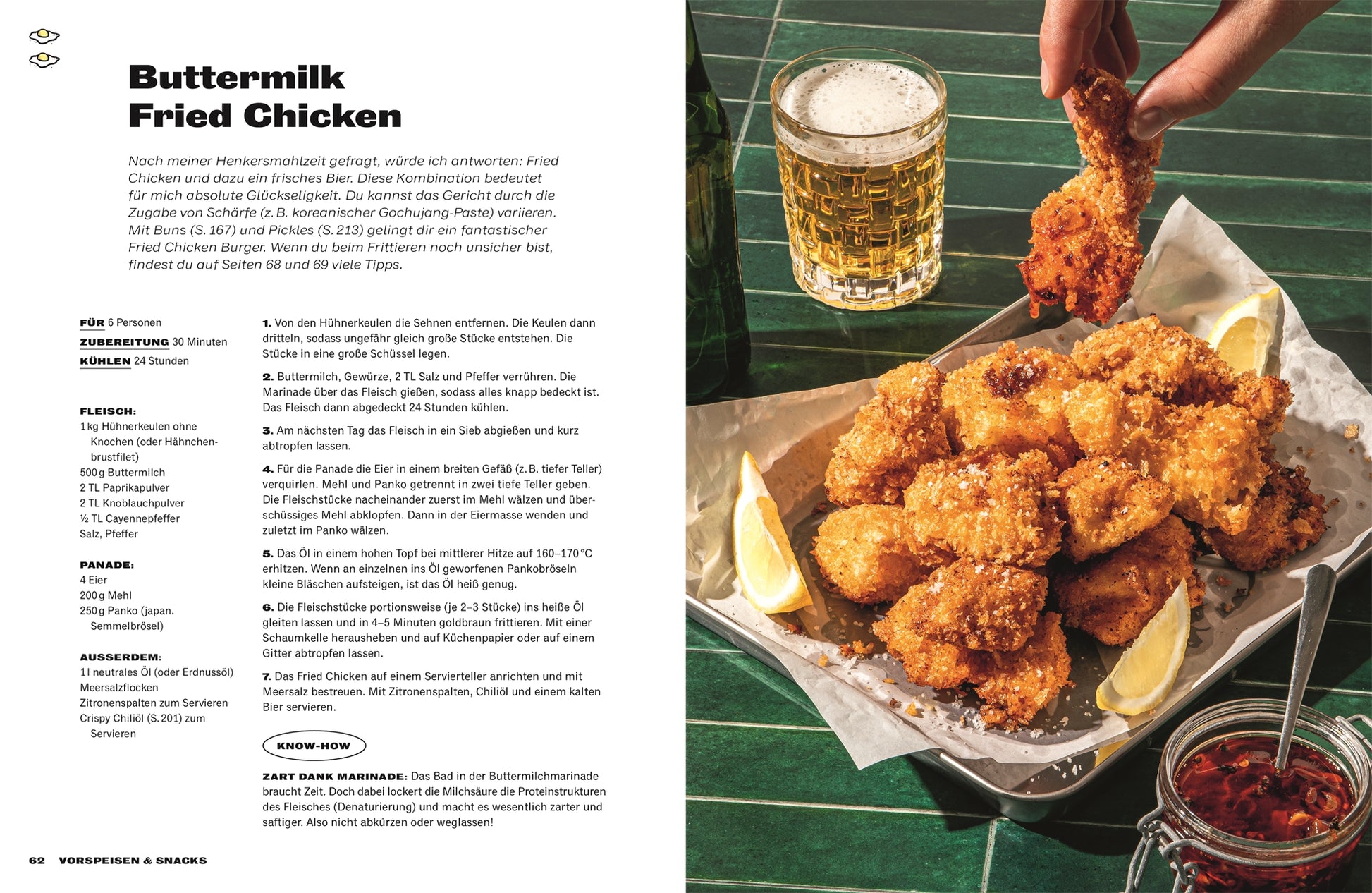Ein Teller mit goldbraunem, knusprigem Buttermilchhähnchen mit Zitronenspalten steht auf einem grün gefliesten Tisch. Inspiriert von „Rezepte in Mach's lecker!“ des DK Verlags taucht eine Hand das Hähnchen in Bier, neben einem weiteren vollen Glas.