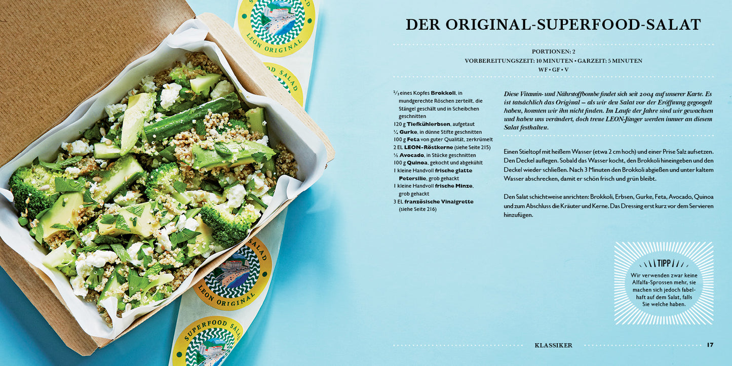 Eine Take-away-Box mit einem leuchtenden LEON. Hundert Salate vom Dumont Verlag – vollgepackt mit Brokkoli, Feta, Avocado, Quinoa und Samen – liegt auf blauem Grund neben zwei Superfoods Original-Packungen. Rechts sind leckere Rezepte zu sehen.