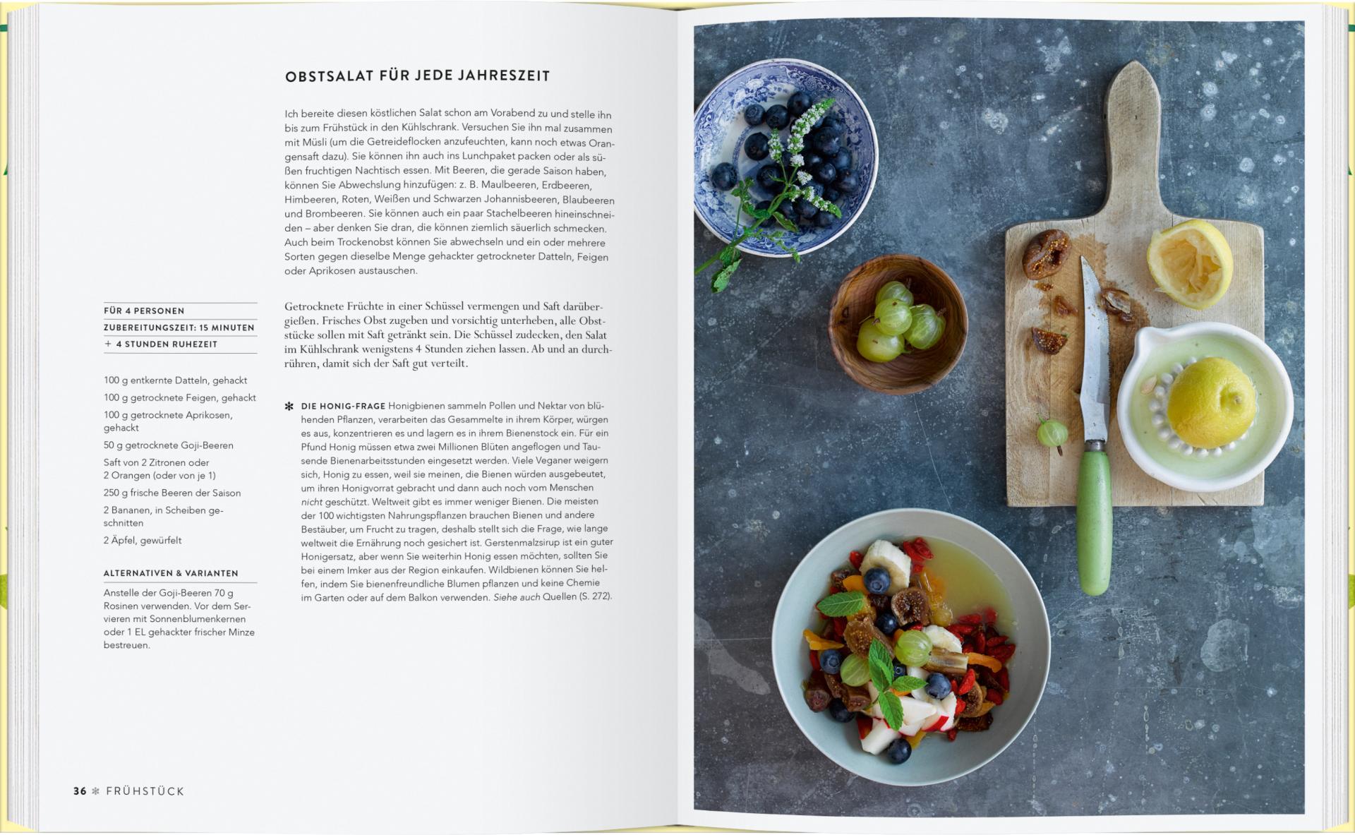 Ein aufgeschlagenes Kochbuch aus dem Gerstenberg Verlag, "Vergnügt Vegan", zeigt ein deutsches Obstsalatrezept und ein Foto von Obstsalat, Früchten und Zitrone - ideal für alle, die vegane Rezepte oder veganes Kochen für die Familie entdecken möchten.