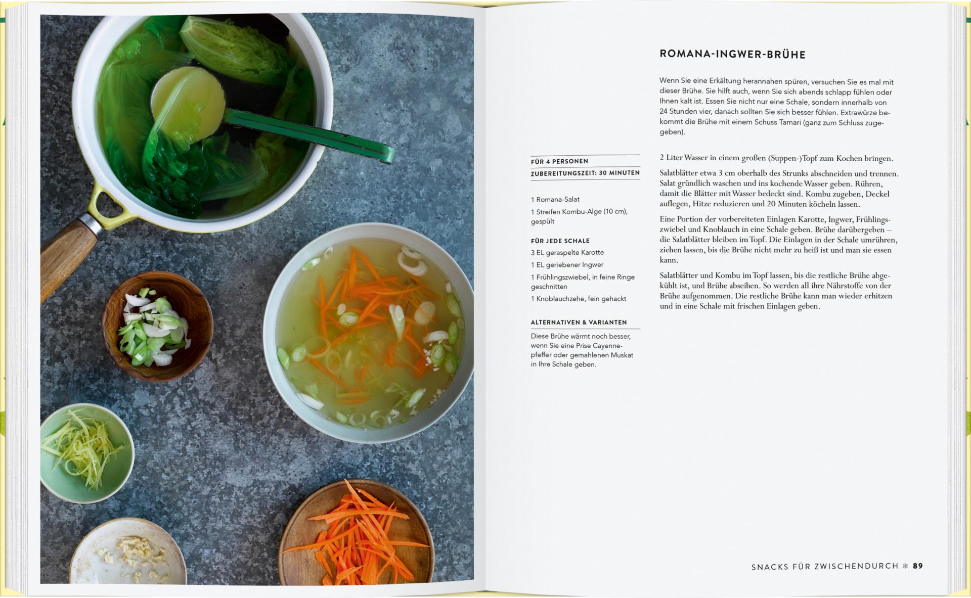 Ein aufgeschlagenes Kochbuch, Vergnügt Vegan vom Gerstenberg Verlag, zeigt ein Rezept für Romana-Ingwerbrühe. Auf blauem Hintergrund liegen Schalen mit klarer veganer Suppe mit Gemüse und Frühlingszwiebeln; auf der rechten Seite steht das deutsche Rezept.