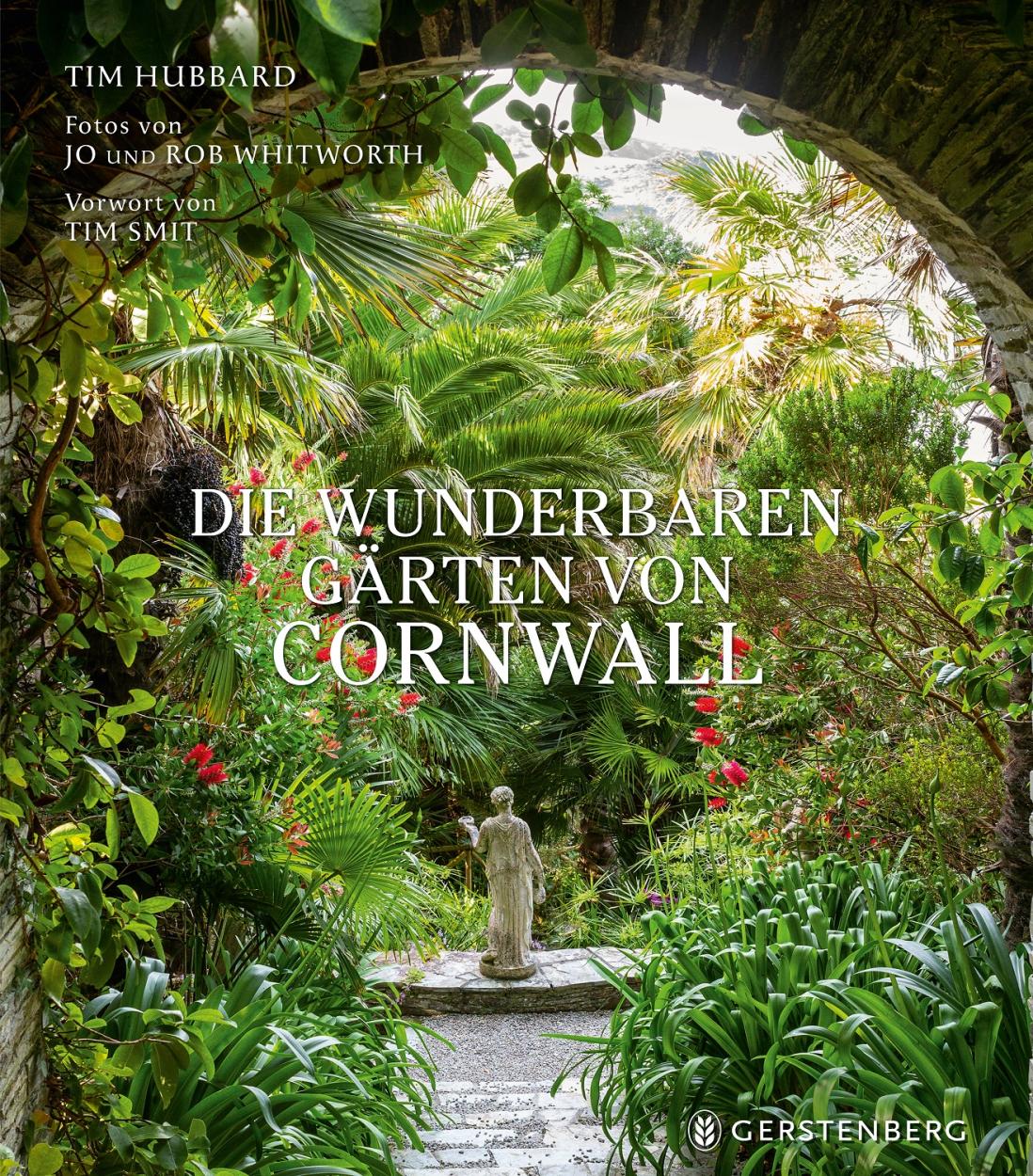 Das Titelbild von Die wunderbaren Gärten von Cornwall (Gerstenberg Verlag) zeigt einen üppigen Garten mit Palmen, roten Blumen und einer Steinstatue, die von einem alten Torbogen eingerahmt wird - eine Einladung, die schönsten englischen Gärten Cornwalls zu entdecken.