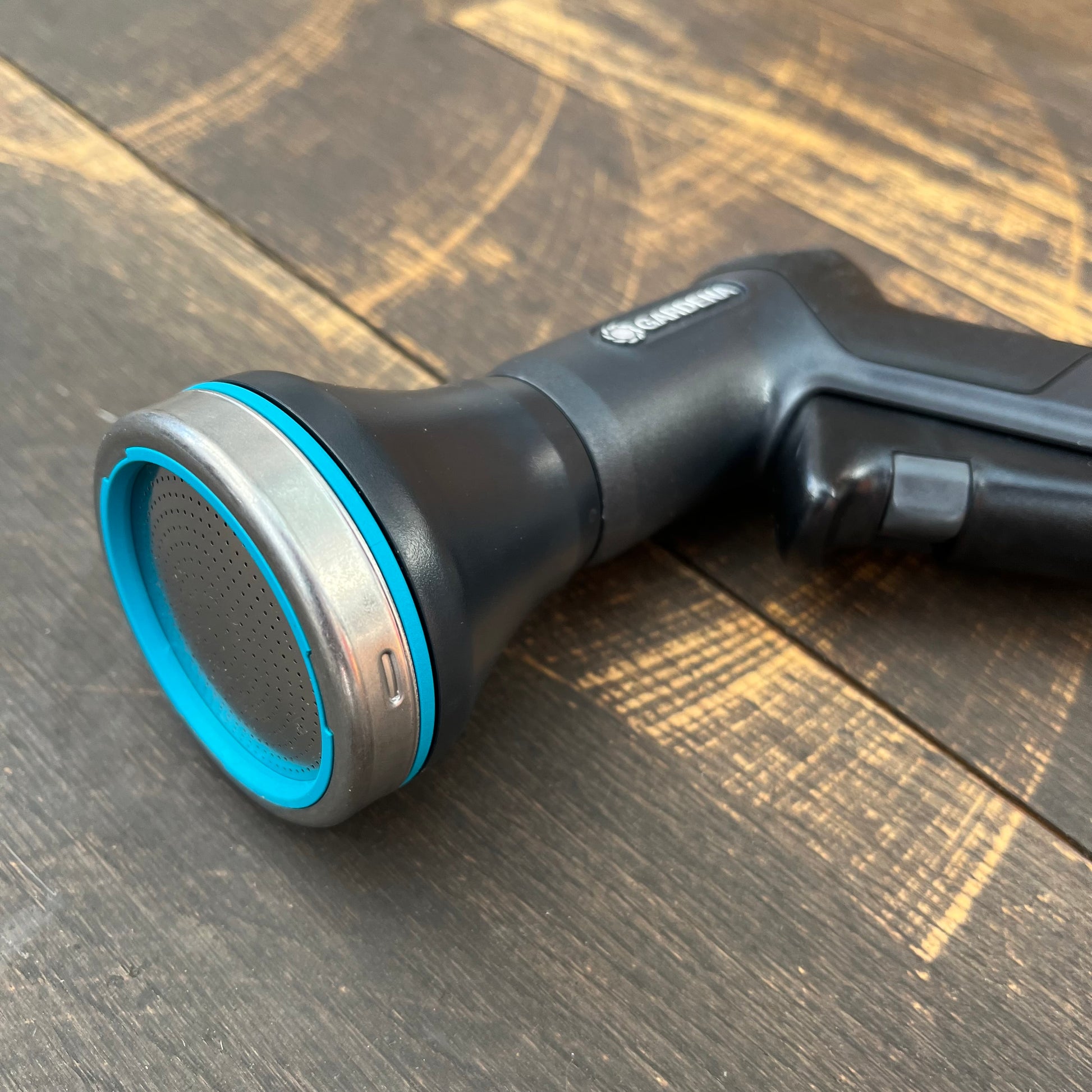 Eine Nahaufnahme der Gardena Eco Line Bewässerungsbrause, einer schwarz-blauen Sprühdüse von Gardena aus recyceltem Kunststoff, die auf Holz ruht - ideal für die nachhaltige Gartenbewässerung.