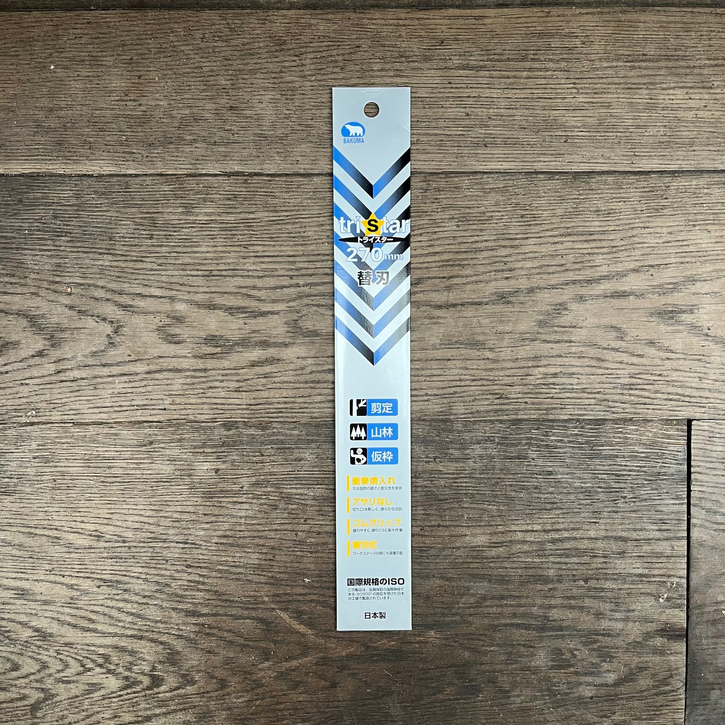 Eine silber-blaue Niwaki-Ersatzklingenverpackung mit der Aufschrift „GR 270“ und japanischem Text liegt auf einem Holzboden. Die Verpackung weist diagonale Streifen und kleine Anwendungssymbole auf und kennzeichnet sie als Premiumprodukt von Niwaki.