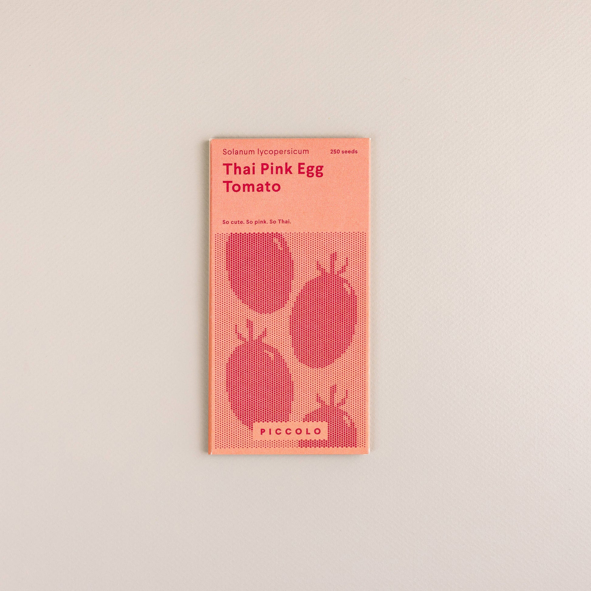 Ein Päckchen Piccolo Seeds - Tomaten-Thai-rosa Ei von Piccolo Seeds, mit einem minimalistischen rosa-roten Design mit drei Tomaten-Illustrationen und Text über diese einzigartige südostasiatische Tomatensorte.