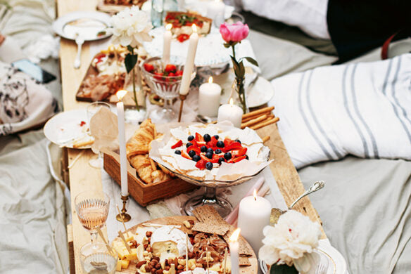 Der "Frühlingstraum" vom Callwey Verlag zeigt einen rustikalen Holztisch mit Kerzen, Blumen und einer Pavlova mit Beeren - die perfekten Dekorationsideen für Ihr elegantes Osterfest oder einen gemütlichen Brunch.