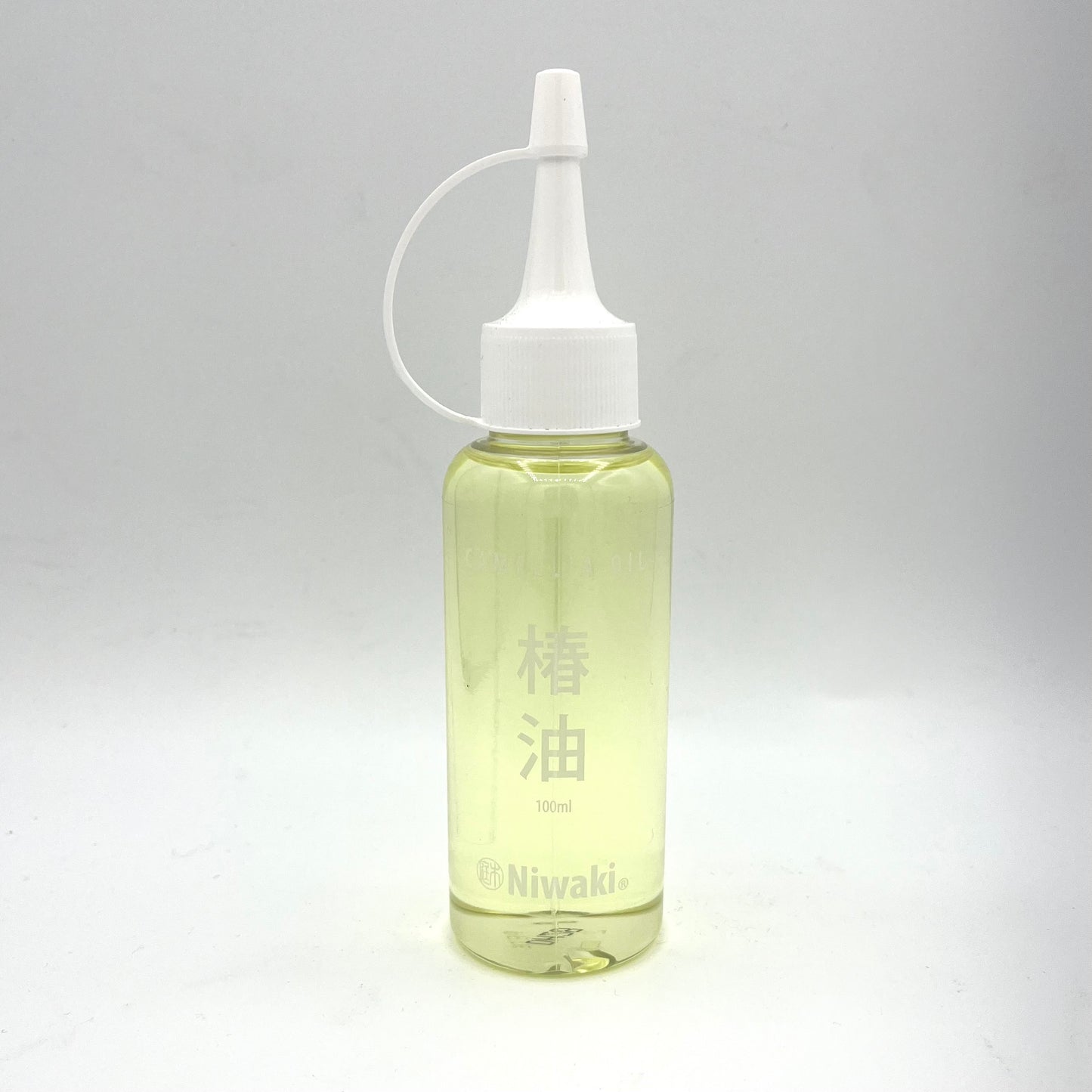 Vor einem schlichten weißen Hintergrund ist eine durchsichtige Plastikflasche mit einem weißen Düsenverschluss zu sehen, die hellgelbes Niwaki-Kamelienöl zur Klingenreinigung und zum Rostschutz enthält und auf Englisch und Japanisch mit „Niwaki“ und „100 ml“ beschriftet ist.