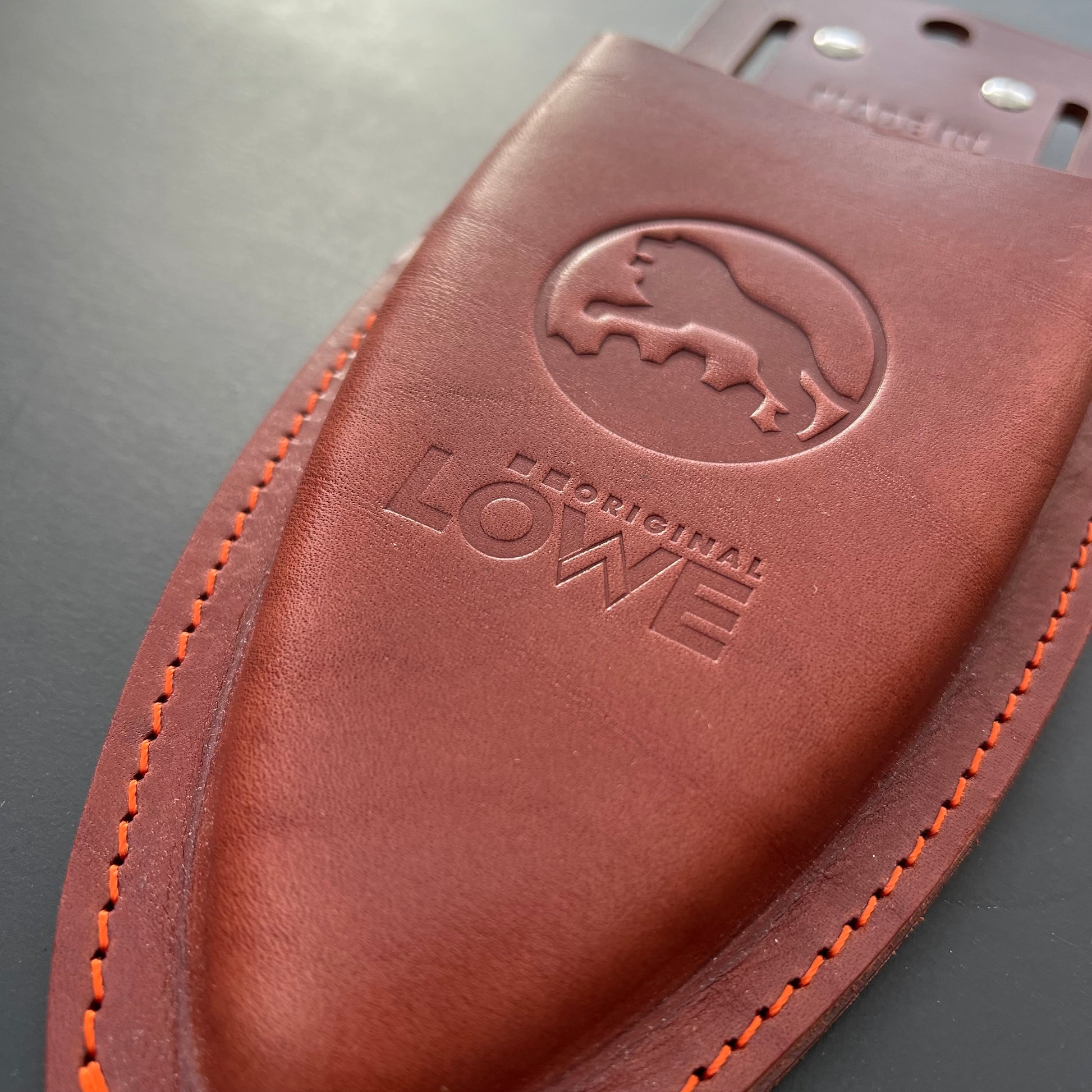 Nahaufnahme des Original Löwe - Lederholster für Gartenscheren von Löwe, aus braunem Leder mit orangefarbenen Nähten, geprägtem Löwenlogo und "The Original LÖWE". Die glatte Scheide ist für eine Gartenschere gedacht und erscheint leer.