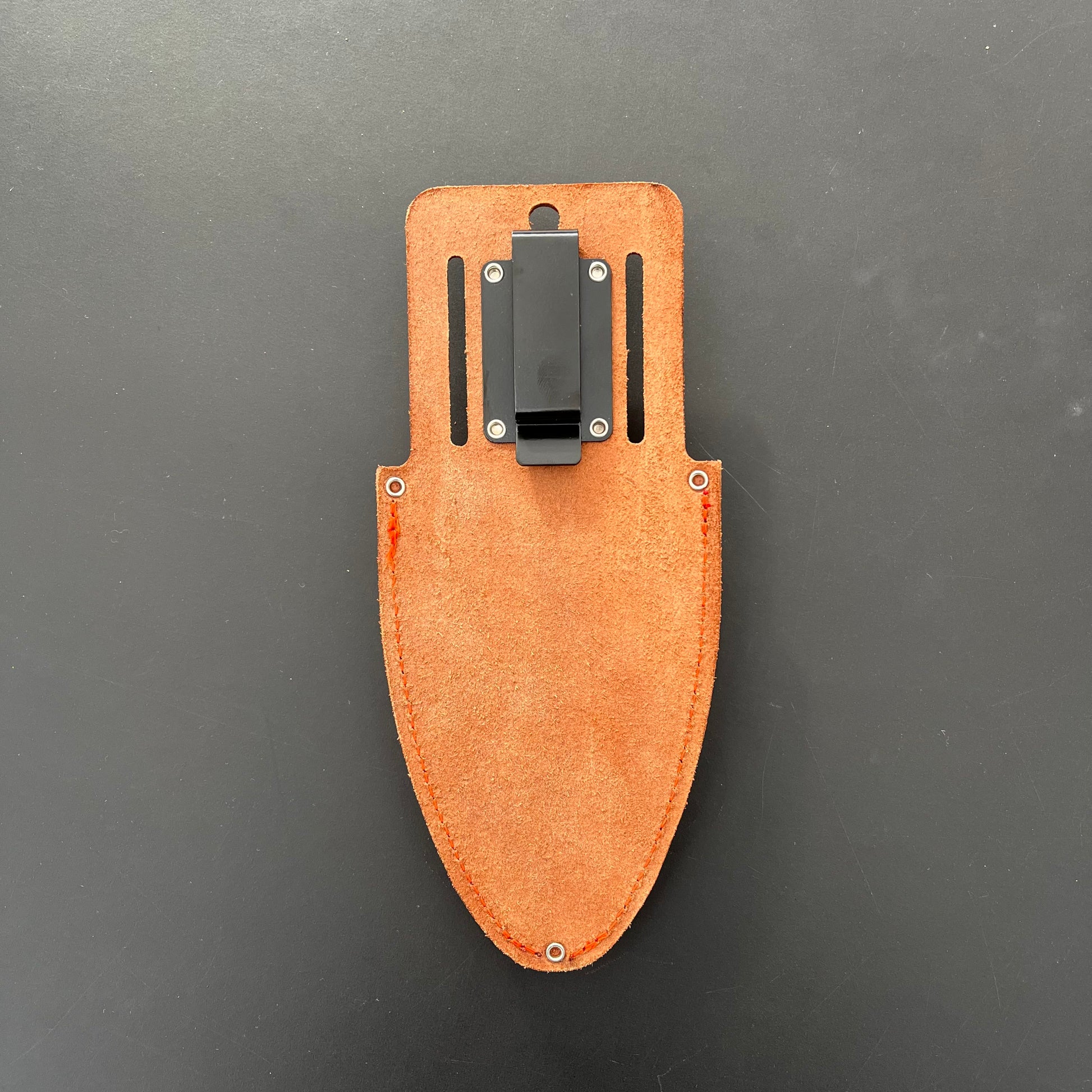 Das Löwe Original Lederholster für Gartenscheren mit hellbraunem Lederdesign, schwarzem Metallgürtelclip und Nieten ist auf einer schlichten dunklen Oberfläche abgebildet.