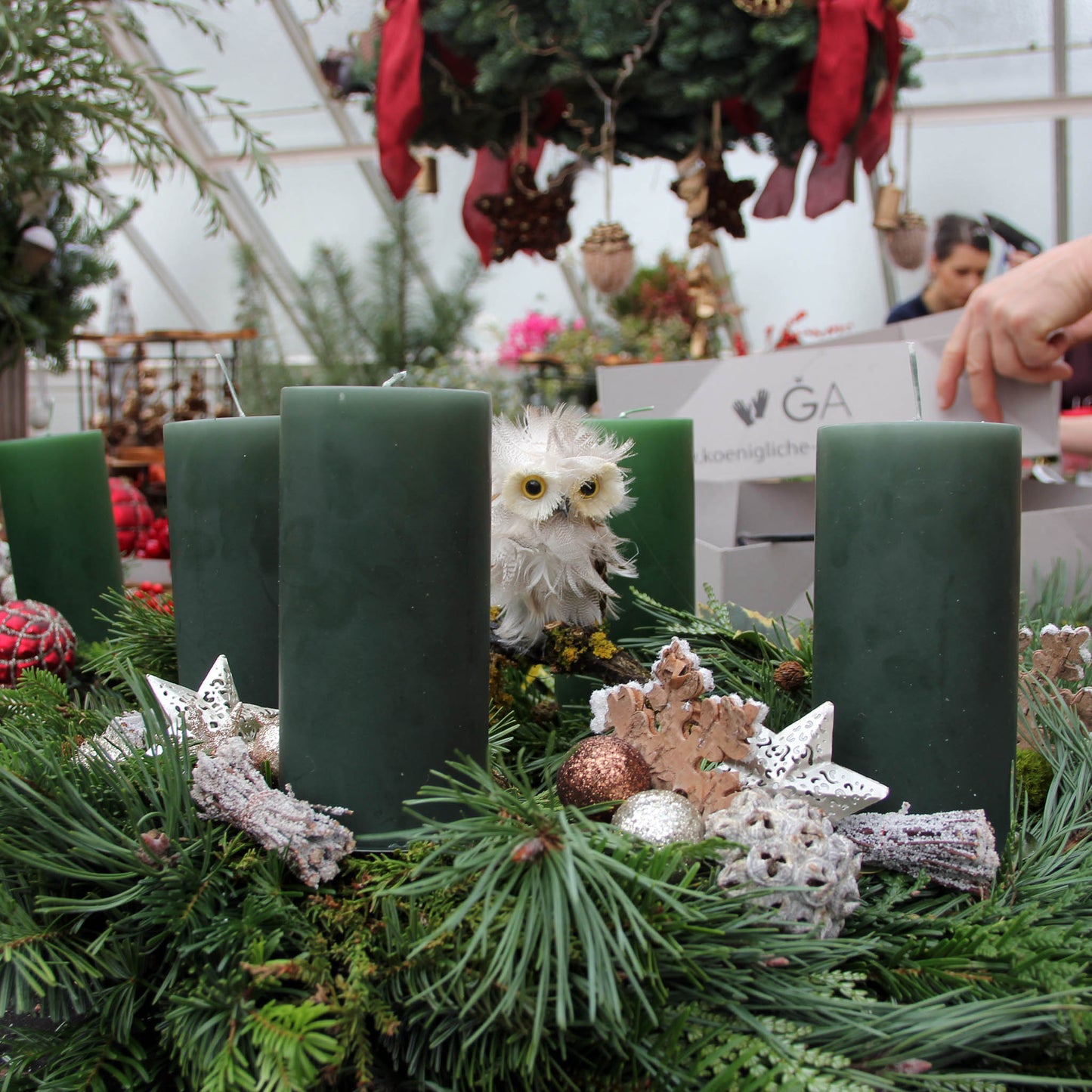 In der Königlichen Gartenakademie können Sie bei dem Workshop "Di. 25.11.2025 | 14.00 - 16.00 Uhr WORKSHOP - Adventskranzbinden bis zu 30 cm" von Thea Carlin gestalten Sie einen Kranz mit vier grünen Kerzen, Tannenzweigen, Zapfen, Sternen, Ornamenten und einer weißen Eule als Mittelstück.