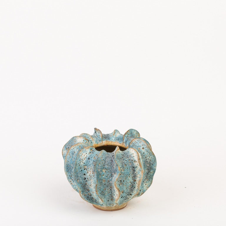 Die Vase von Des Pots | Moos Klein in Blaugrün von Des Pots ist eine kleine, runde, handgeformte Steingutvase mit wellenförmigem Rand und strukturierter blaugrüner Glasur, kürbisähnlich geformt auf weißem Hintergrund.