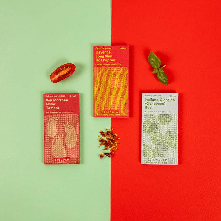 Drei farbenfrohe Päckchen „Piccolo Seeds – Tomatensoße“ von Piccolo Seeds werden auf einem gespaltenen grün-roten Hintergrund präsentiert, begleitet von einer Tomatenhälfte, Basilikumblättern und Pfefferflocken.