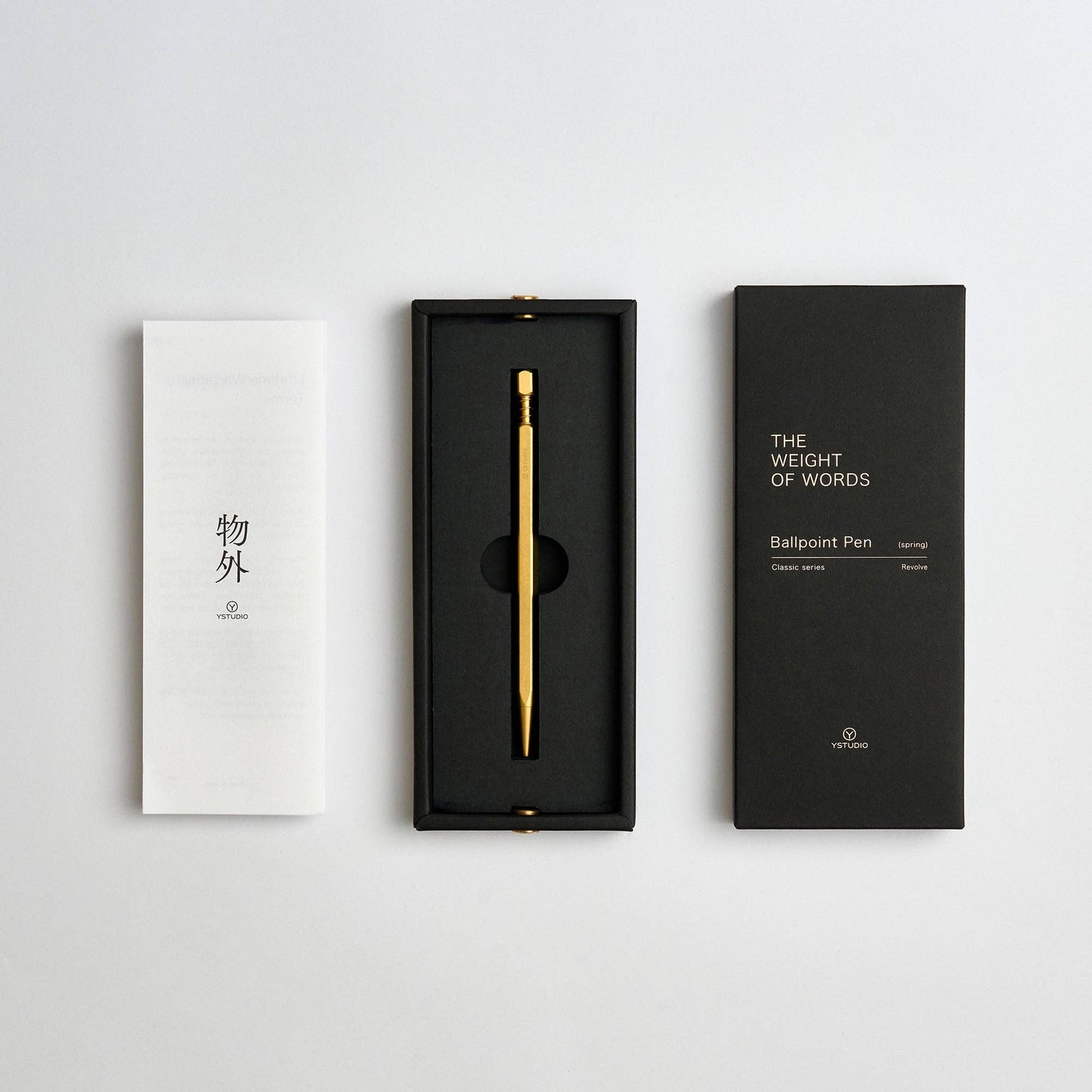 Ein langlebiger ENTREPÔT - YSTUDIO Klassischer Revolve Kugelschreiber aus massivem Messing (Gold) liegt in einer schwarzen Box, begleitet von zwei rechteckigen Booklets auf weißem Hintergrund.