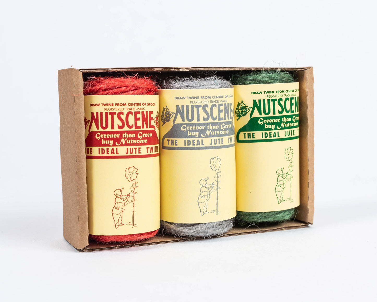Drei 42-Fuß-Minirollen Nutscene Twines Ltd - rot, natürlich und grün - sind in einem Kartonhalter abgebildet. Jede Rolle in diesem 3er-Pack hat ein Etikett im Vintage-Stil mit einer Illustration und Text. Biologisch abbaubare Schnur.