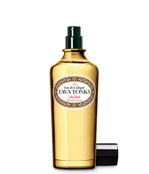 Der goldgelbe Glasflakon von Ach.Brito - Eau de Cologne - Fava Tonka 100 ml hat einen schwarzen Sprühkopf, ein weißes Etikett mit dunkler Schrift und eine Kappe daneben, die den einzigartigen Tonkabohnen-Duft dieses Ach.Brito-Duftes hervorhebt.