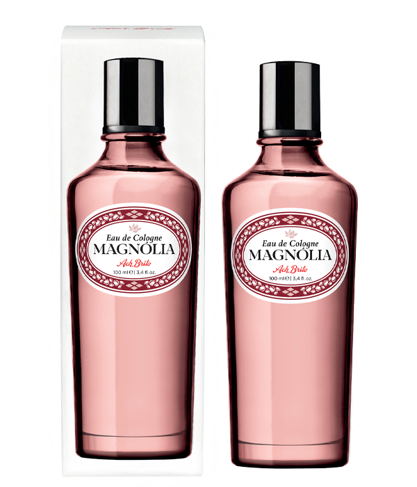 Der rosa Glasflakon von Ach.Brito - Eau de Cologne - Magnolia 100 ml mit weißem Etikett und rotem Rand wird zusammen mit der dazugehörigen Schachtel gezeigt. Dieser Duft bietet einen blumigen Duft, der perfekt für jede Gelegenheit ist.
