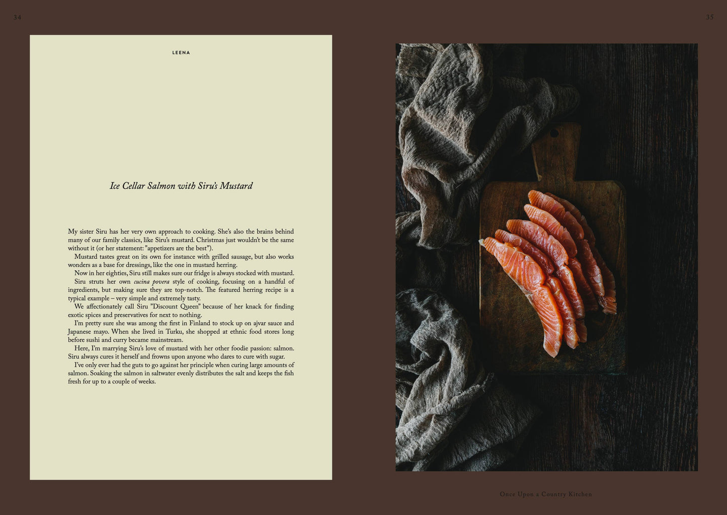 Eine Draufsicht auf geschnittenen Lachs auf einem Holzbrett mit stimmungsvoller Beleuchtung schafft neben dem Kochbuch „Once upon a country kitchen“ von Cozy Publishing eine rustikale Küchenszene.