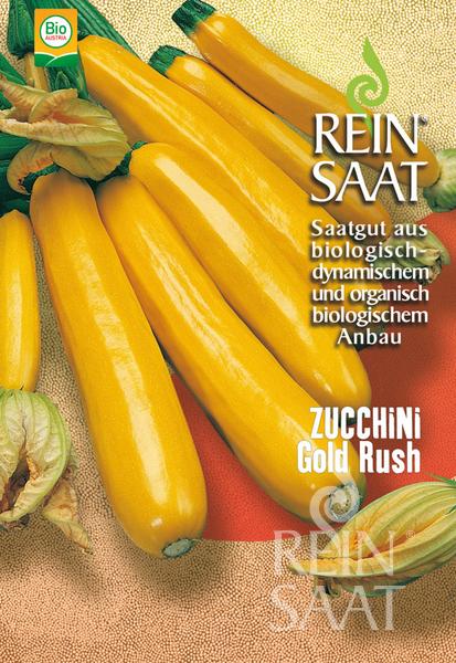 Eine Nahaufnahme von mehreren goldgelben Zucchini mit Blüten auf einer gelben Oberfläche. Auf der Verpackung steht Reinsaat, Zucchini 'Gold Rush', und Bio-Saatgut auf Deutsch.