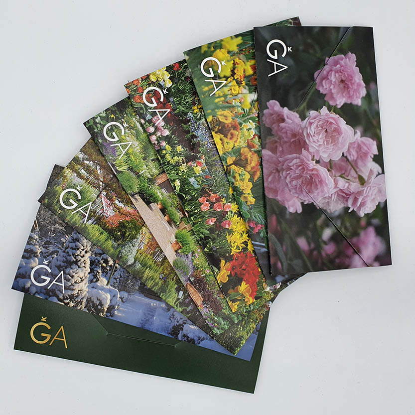 Ein aufgefächerter Satz bunter Karten mit Gartenfotos aus allen Jahreszeiten, auf denen das Logo der Königlichen Gartenakademie, eine Krone und „Gutschein für die Königliche Gartenakademie“ aufgedruckt sind.