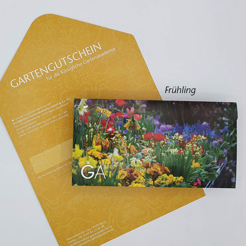 Ein gelber Umschlag des Gutscheins für die Königliche Gartenakademie von der Königlichen Gartenakademie ist mit Blumenmustern versehen und teilweise mit einer farbenfrohen Frühlingskarte mit „Frühling“ und deutschem Text der renommierten Gartenakademie bedeckt.