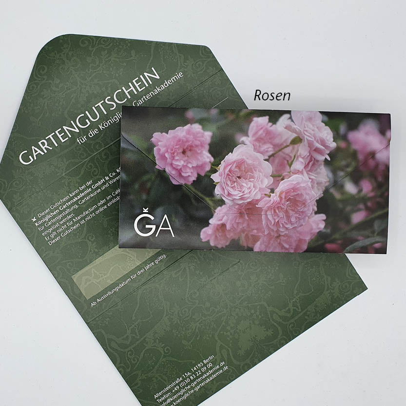 Ein grüner Gutschein für die Königliche Gartenakademie der Königlichen Gartenakademie mit weißem Text liegt teilweise in einem passenden Umschlag. Oben ist eine Karte mit rosa Rosen, den Buchstaben GA und dem Wort Rosen darüber.