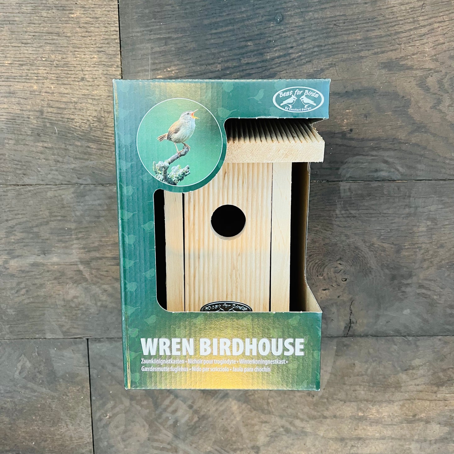 Auf Holz ist ein Esschert Nistkasten aus zertifiziertem Erlenholz mit rundem Eingang ausgestellt. Die Verpackung zeigt ein Zaunkönigbild, den Text „Wren Birdhouse“ und weist darauf hin, dass es sich um verschiedene Vogelarten und Nistkästen handelt.