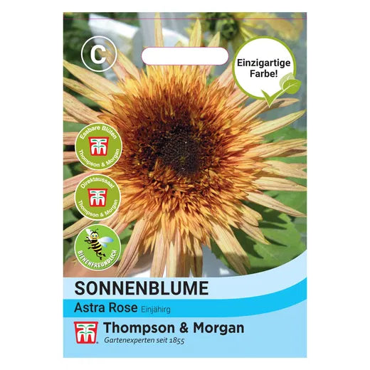 Eine Saatgutpackung der Thompson&Morgan Sonnenblume 'Astra Rose' zeigt rosarote und gelbe Blüten in Nahaufnahme, die als bienenfreundlich und essbar gekennzeichnet sind.
