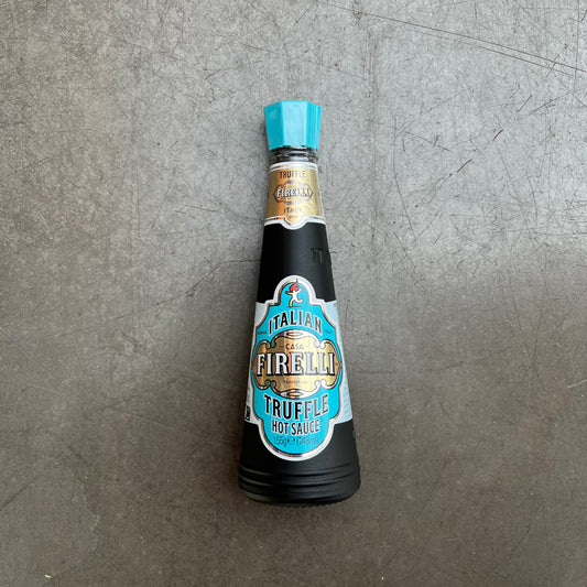Eine 148 ml Glasflasche Firelli - Casa Firelli Scharfe Sauce mit italienischen Trüffeln steht auf einer grauen, strukturierten Oberfläche.