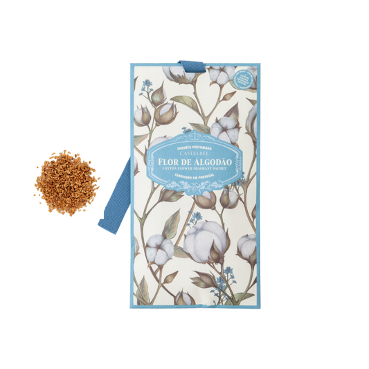 Ein Castelbel Sachet | Cotton Flower 10 g, verziert mit floraler Baumwollkunst und der blauen Aufschrift "Flor de Algodão", ruht neben einem kleinen Haufen brauner Duftgranulate und bietet einen lang anhaltenden Cotton Flower Duft auf weißem Grund.