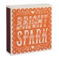 Die Archivist Gallery Bright Spark Quadratische Streichholzschachteln ist eine quadratische orange-weiße Streichholzschachtel mit dekorativen Mustern und dem Schriftzug BRIGHT SPARK" auf der Vorderseite.