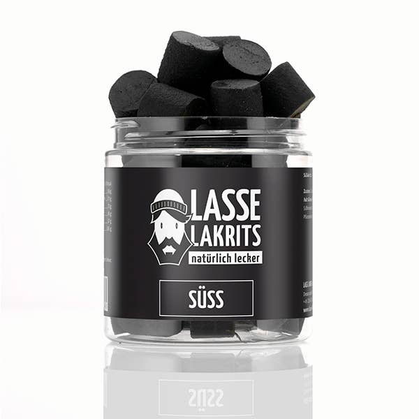 Das durchsichtige Glas LASSE LAKRITS - natürlich lecker - Dose Lakritz Süss mit süßen Lakritzstückchen trägt das LASSE LAKRITS-Logo mit dem bärtigen Gesicht auf einem schwarz-weißen Etikett, das auf einer weißen, reflektierenden Oberfläche angebracht ist.