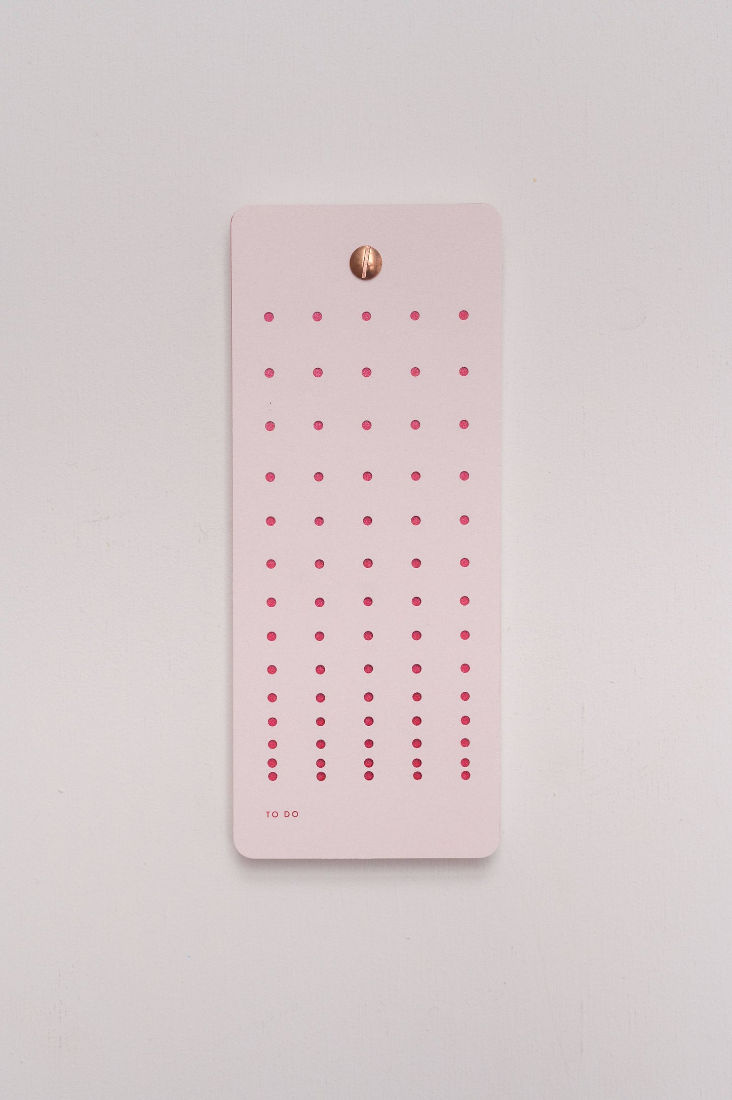 Der Tinne Mia - Aufgabenliste - Mellow Rose ist ein rosafarbener Aufgabenblock von Tinne Mia aus FSC-zertifiziertem Papier mit kleinen rosafarbenen Farbverläufen und einem goldenen Verschluss an der Oberseite, der vor einem hellen Hintergrund abgebildet ist.