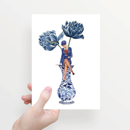 Eine Hand hält die Lylies Grußkarte: Zur Hälfte gefaltet, mit Damenumschlag auf einer blauen Vase und zwei großen blauen Blumen im Hintergrund.