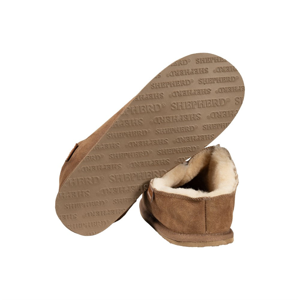Ein Paar Shepherd of Sweden Richard Slipper aus Schaffell in Cognac (Größe 42) mit cremefarbenem Shearling-Futter; ein Slipper steht aufrecht, der andere ist umgedreht, so dass eine Sohle mit mehrfacher Prägung von "SHEPHERD" und "ORIGINALS" zu sehen ist.