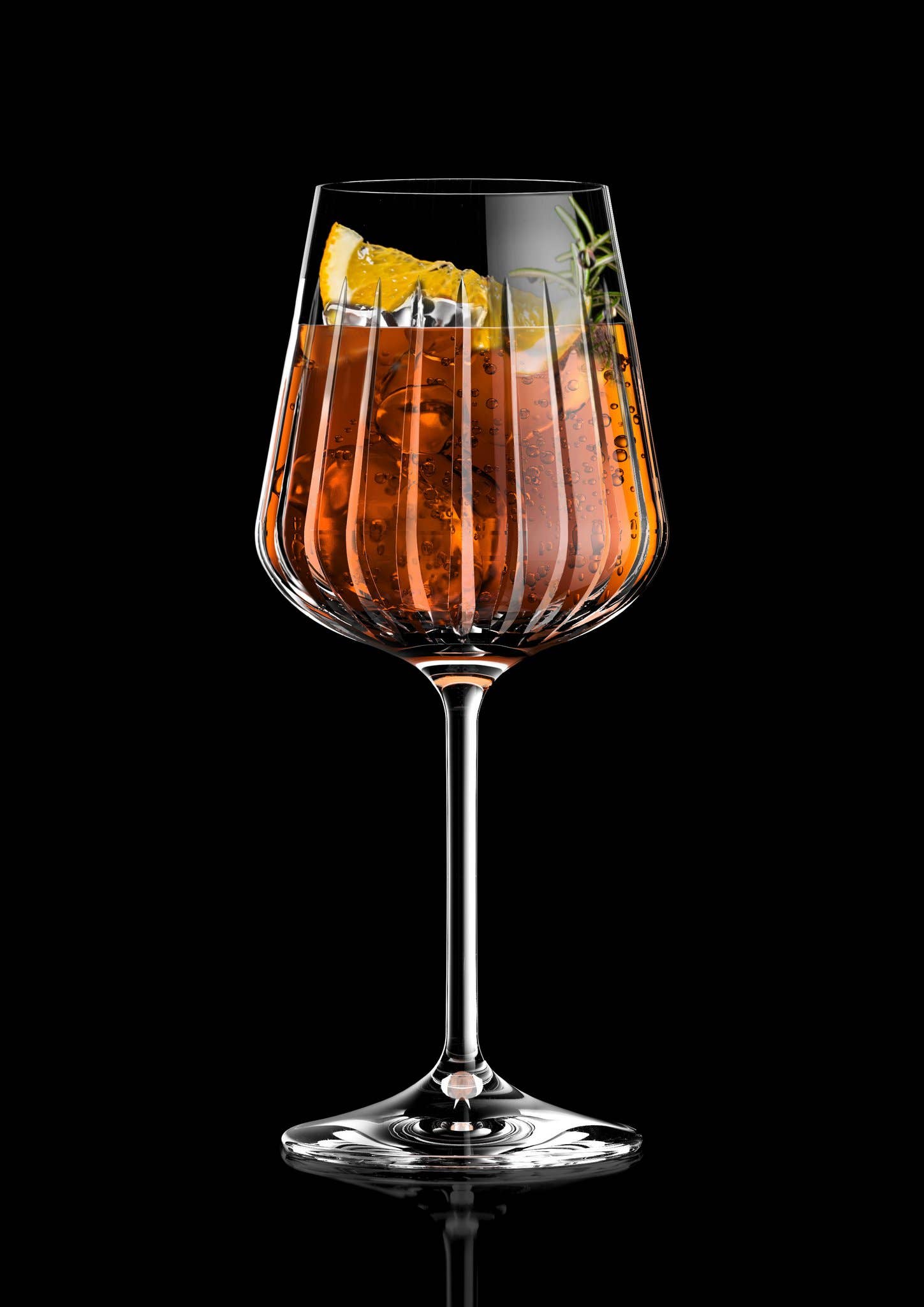 Ein RCR Cristalleria Spritzglas 51 cl Timeless, gefüllt mit einem Orangencocktail, Eiswürfeln, einer Zitronenspalte und Rosmarin, steht vor einem schwarzen Hintergrund.