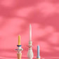 Drei lebendige IB Laursen Kerzenhalter aus Keramik - zwei in weiß / blau gemustert und einer in rosa - zeigen pastellfarbene Kerzen (gelb, rosa, blau) mit dekorativen Mustern auf einem rosa Hintergrund und weichen Schatten.