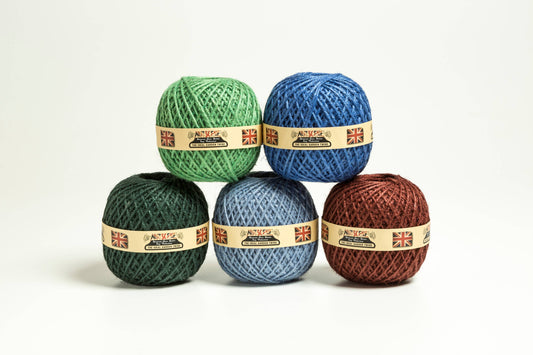 Fünf Nutscene Twines Ltd Heritage Twine Kugeln in grün, blau und braun sind pyramidenförmig auf weißem Hintergrund gestapelt. Jeder Jute-Schnurbälle hat ein Etikett mit britischen Flaggen und Branding.