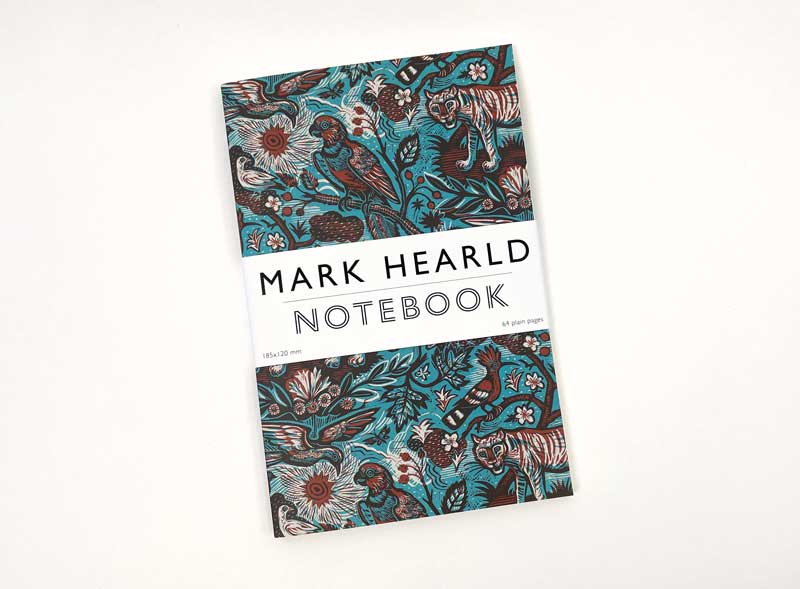 Das Art Angels Tyger Tyger Notizbuch von Mark Hearld hat ein leuchtend blaugrünes und braunes Cover mit Vögeln, Blumen und Tigern sowie ein weißes Band mit der Aufschrift "MARK HEARLD NOTEBOOK", das den farbenfrohen Stil des Künstlers widerspiegelt.