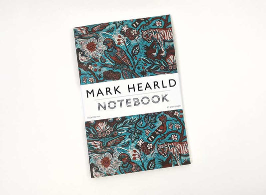 Das Art Angels Tyger Tyger Notizbuch von Mark Hearld hat ein leuchtend blaugrünes und braunes Cover mit Vögeln, Blumen und Tigern sowie ein weißes Band mit der Aufschrift "MARK HEARLD NOTEBOOK", das den farbenfrohen Stil des Künstlers widerspiegelt.