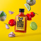 Eine Flasche Crazy Bastard Sauce - Habanero & Tomatillo 100 ml von CBS Foods GmbH steht auf einem gelben Hintergrund, umgeben von Habanero-Schoten, Tomatillos, Knoblauchzehen und Limettenhälften - ideal für Liebhaber scharfer Soße.