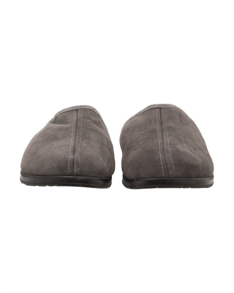 Der Ludvig Slipper aus Schaffell in Asphalt 42 von Shepherd of Sweden, hier von vorne auf weißem Grund, bietet mit seiner grauen Wildlederoptik und der schwarzen Sohle gemütlichen Komfort und klassischen Stil.