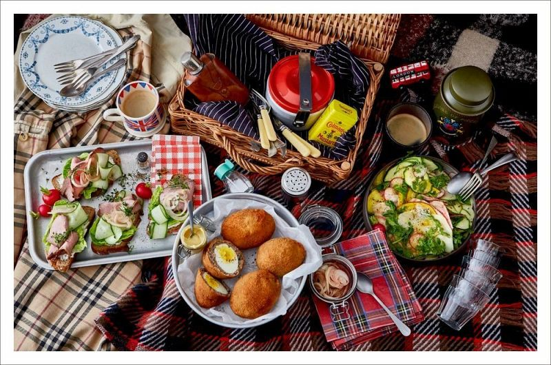 Inspiriert von *London Lovestory* aus dem Hölker Verlag, fängt ein Picknick mit Sandwiches, Scotch-Eiern, Salat, Getränken und einem Weidenkorb die Romantik der britischen Küche ein - perfekt für alle, die in London eine gemütliche Atmosphäre im Freien suchen.